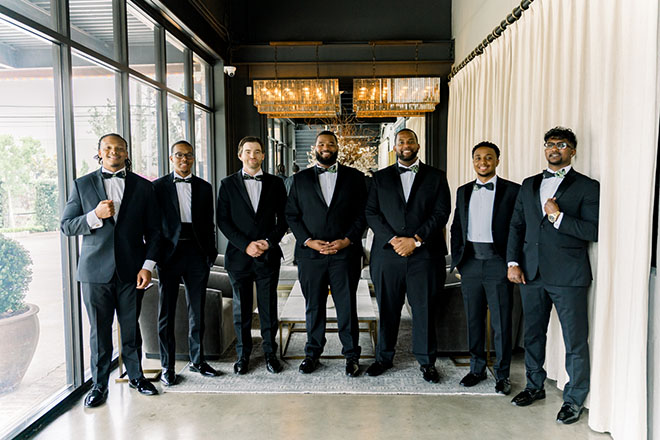 The groom and his groomsmen stand in the atrium of The Astorian. 