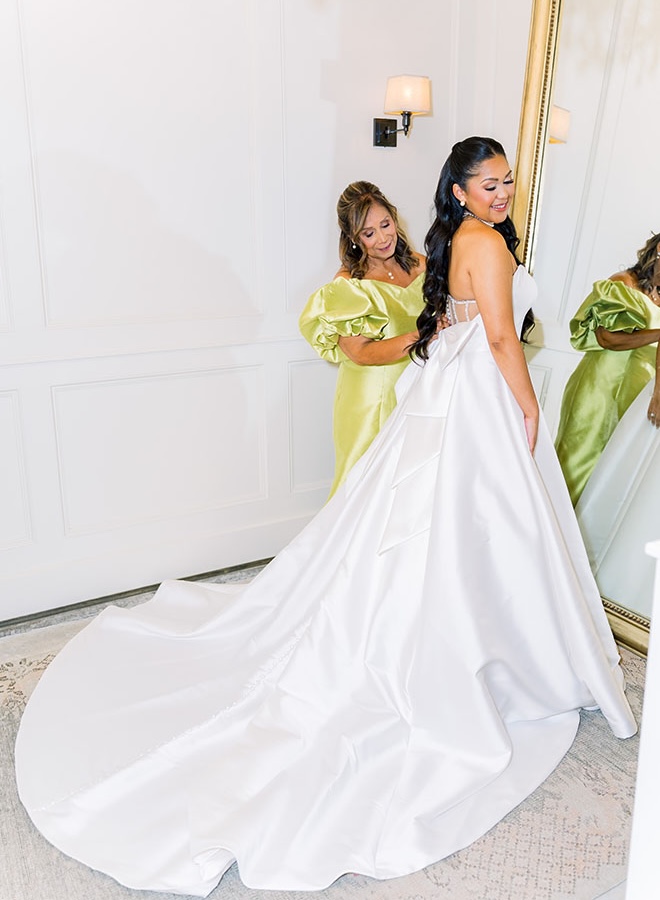 The mother of the bride helps her daughter into her wedding dress. 