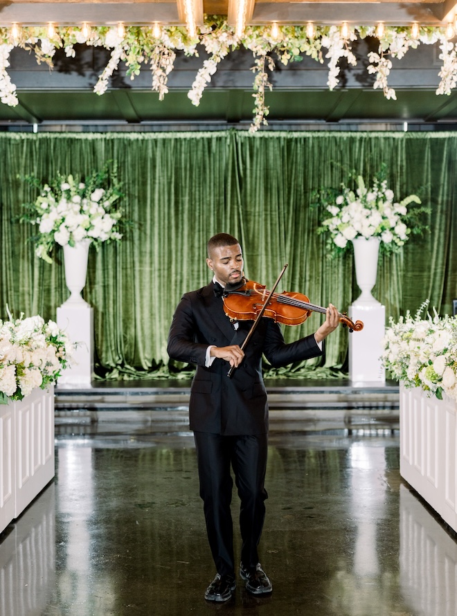 A violinist plays at the emerald green wedding ceremony at The Astorian.  