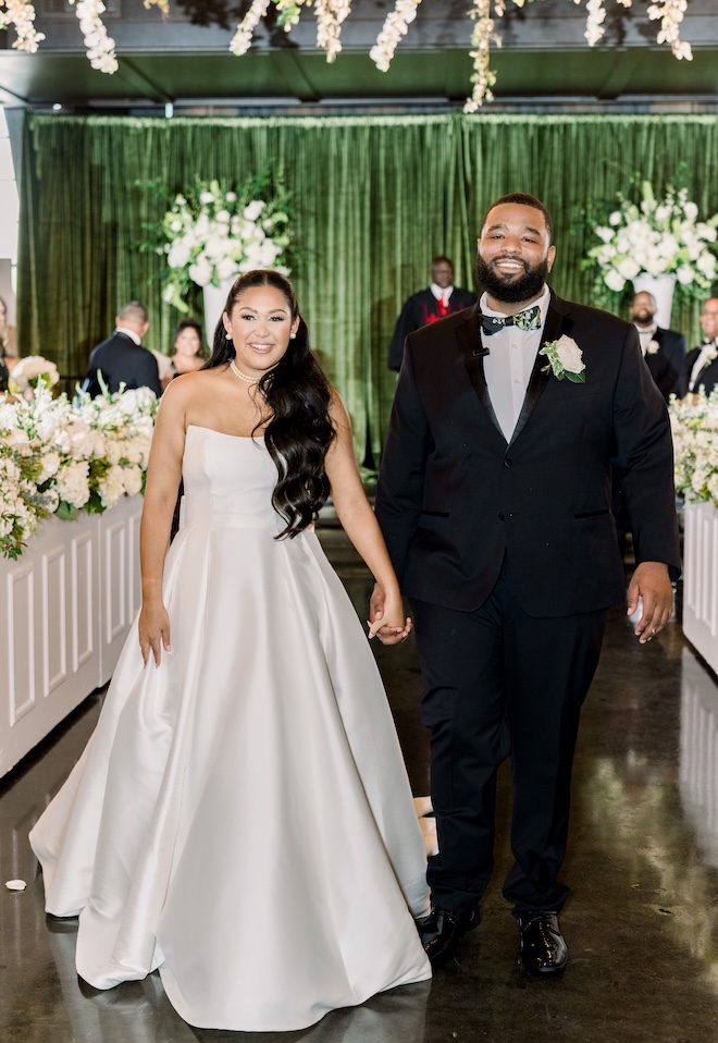 The couple hold hands as they walk down the aisle after their ceremony. 