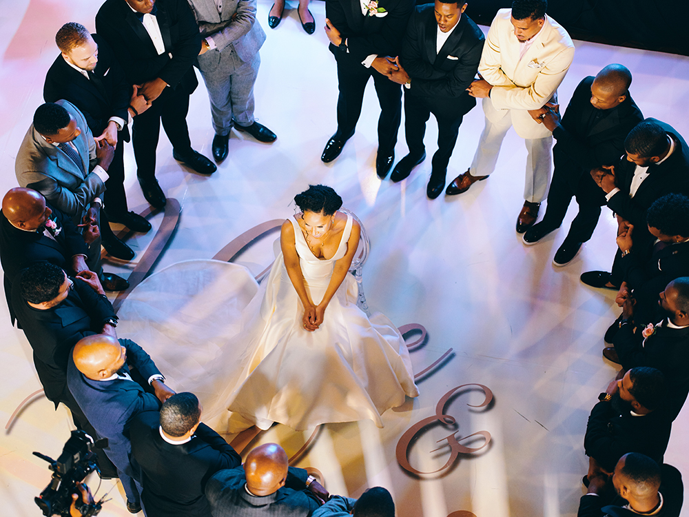 bride surrounded by groomsmen in a circle for a prayer 