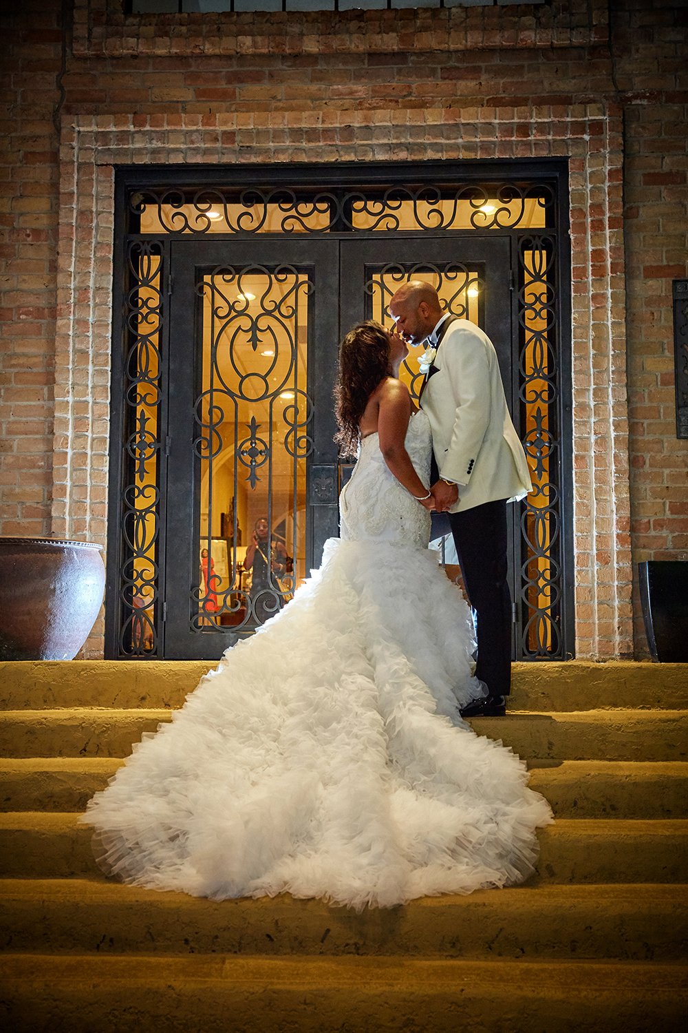 couple on the stairs at the end of the night, wedding dress with lush train and details feathers