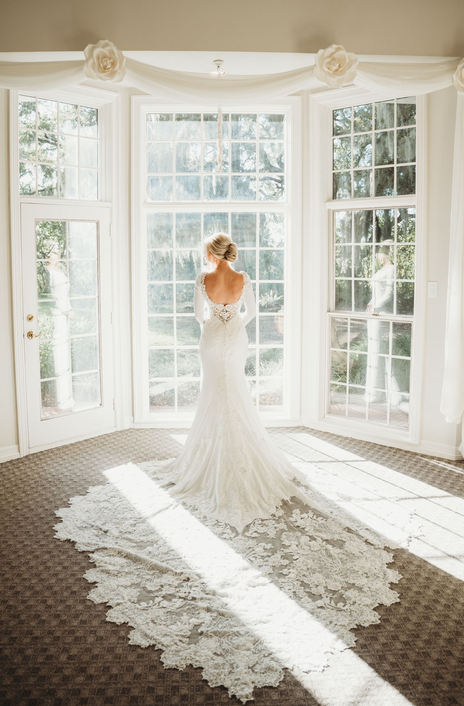 Bride in front of bright bay windows. 